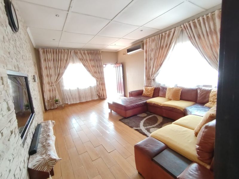 Spacious living room featuring tiled flooring, a stone-cladding feature wall, and a split-system air conditioner, offering a comfortable and functional living space.