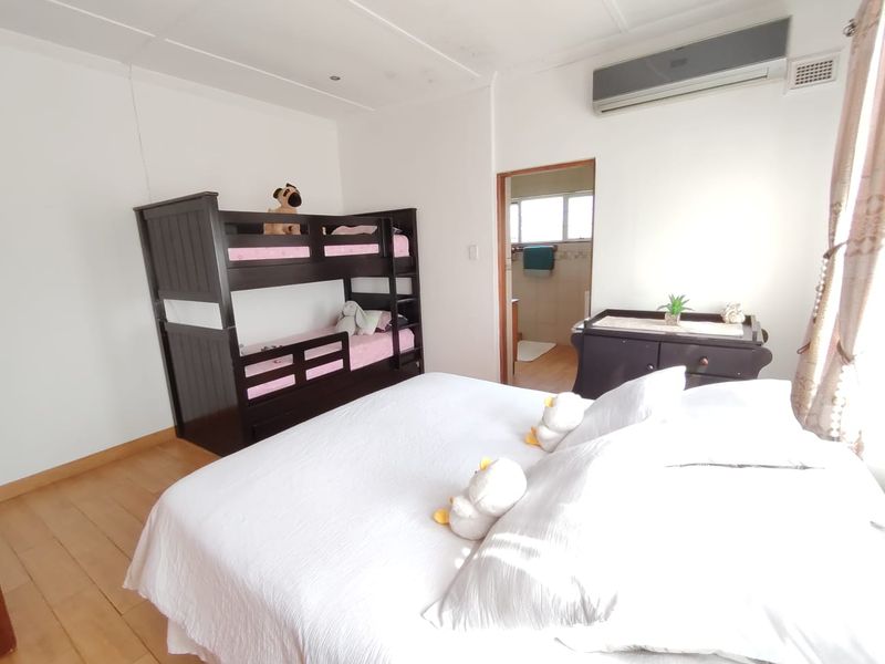A bedroom featuring laminate flooring, an air conditioning unit, and direct access to an en-suite bathroom.