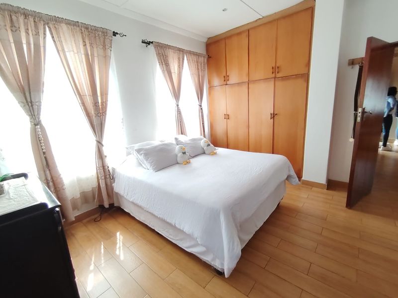 A bedroom featuring laminate flooring, recessed lighting, and extensive built-in wooden cabinetry for storage.