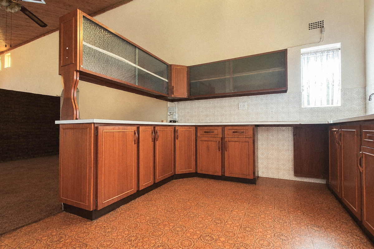 A spacious, dated kitchen featuring extensive wooden cabinetry, tiled backsplash, and traditional tiled flooring, offering significant potential for a modern renovation.