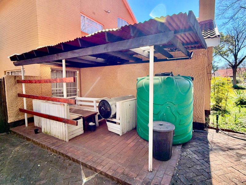 Covered outdoor patio area featuring paved flooring, timber structure, and a large water storage tank.