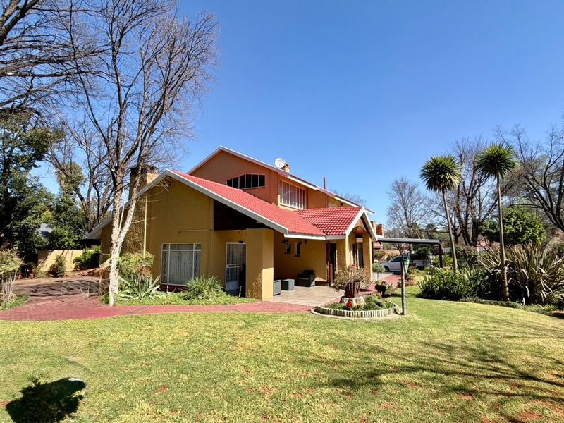 A view of the rear elevation of the house featuring a red tiled roof, covered patio area, and a well-maintained garden.