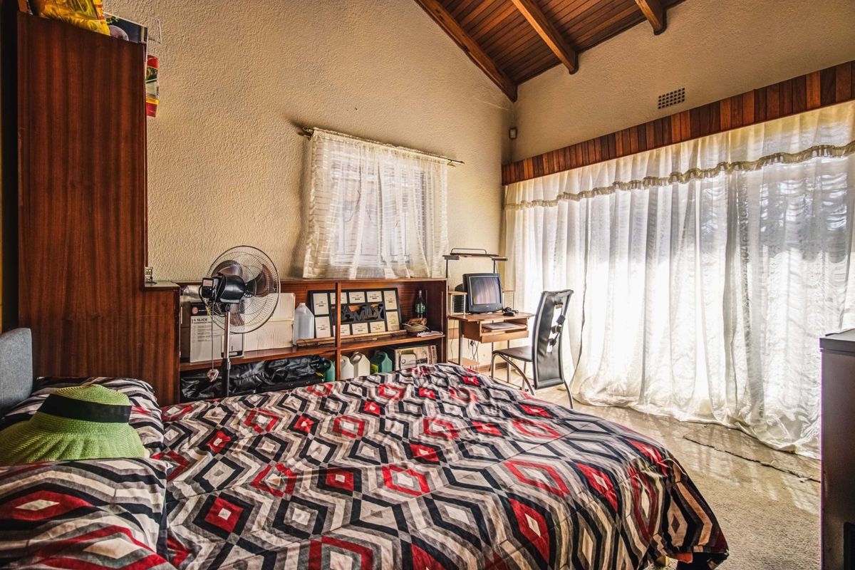 Spacious bedroom featuring a high vaulted timber ceiling with exposed beams and built-in timber cabinetry, offering a classic aesthetic with potential for modernization.