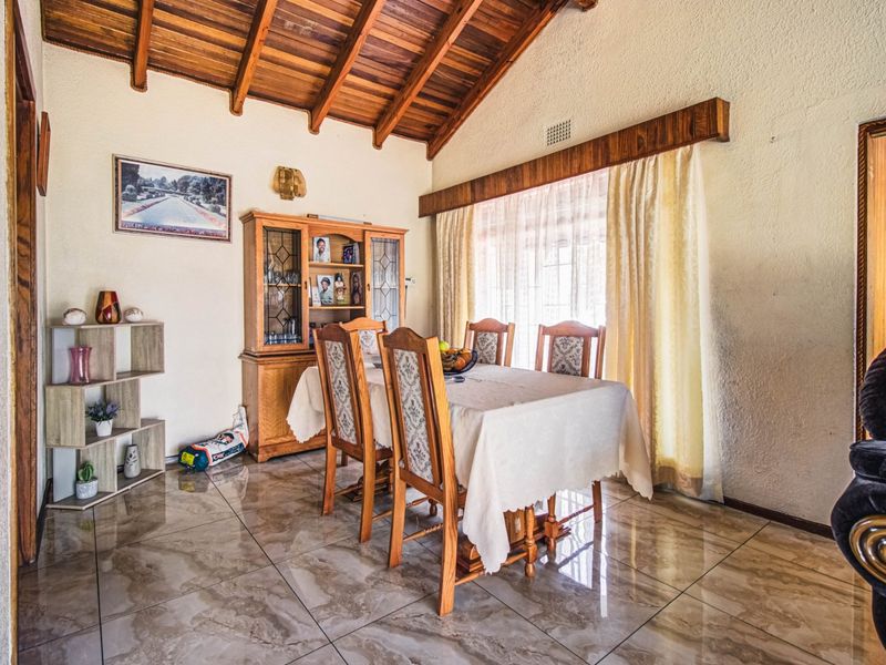 Dining room featuring exposed timber ceiling beams, tiled flooring, and a timber window pelmet, offering a warm and traditional aesthetic.