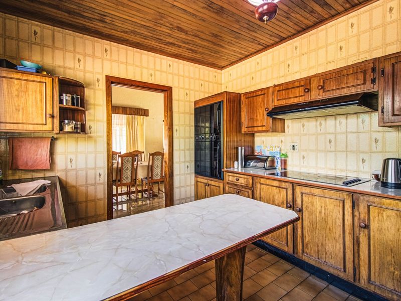 A dated kitchen featuring wooden cabinetry, a built-in oven, extractor fan, and tiled finishes, offering significant potential for a modern renovation.