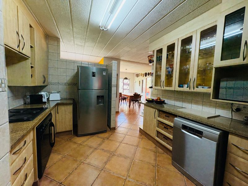 A functional kitchen featuring light wood cabinetry, granite countertops, tiled flooring, and a tiled backsplash, with an open-plan flow toward the dining area.