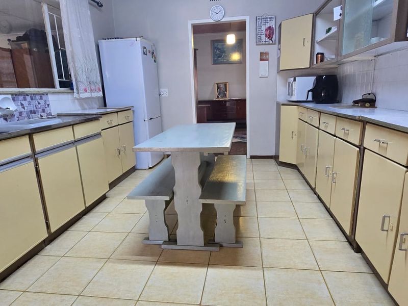 A functional kitchen featuring dated laminate cabinetry, tiled flooring, and a tiled backsplash, offering significant potential for a modern renovation.