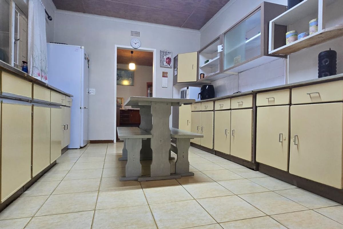 A functional kitchen featuring extensive built-in cabinetry, tiled flooring, and a central dining area, offering significant potential for modern renovation.