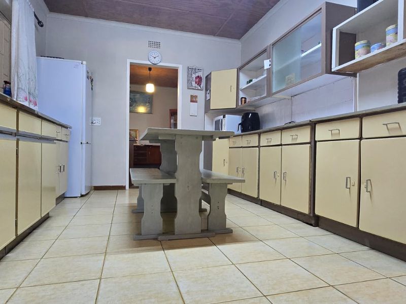 A functional kitchen featuring extensive built-in cabinetry, tiled flooring, and a central dining area, offering significant potential for modern renovation.