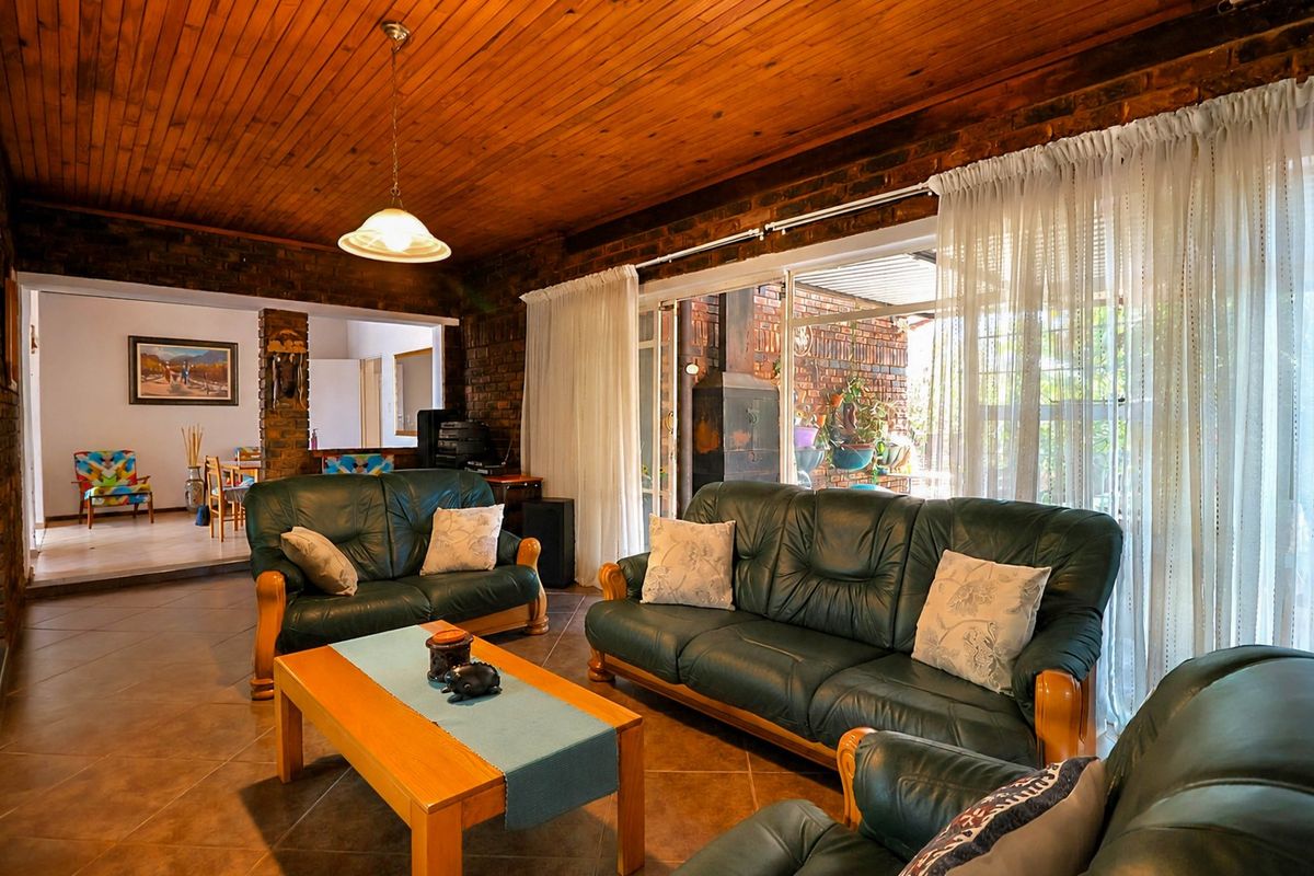 Spacious living room featuring exposed brick walls, a warm timber ceiling, and large sliding glass doors that provide access to the outdoor patio area.