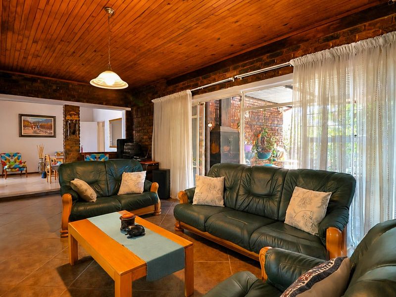 Spacious living room featuring exposed brick walls, a warm timber ceiling, and large sliding glass doors that provide access to the outdoor patio area.