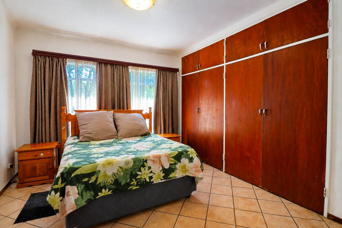 A bedroom featuring tiled flooring and extensive built-in wooden cupboards, offering ample storage space.