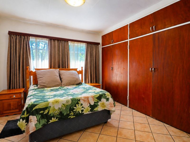 A bedroom featuring tiled flooring and extensive built-in wooden cupboards, offering ample storage space.