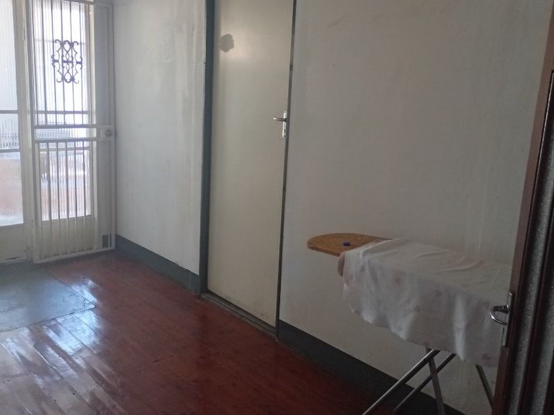 A functional hallway featuring timber flooring and a security gate, providing access to internal rooms.
