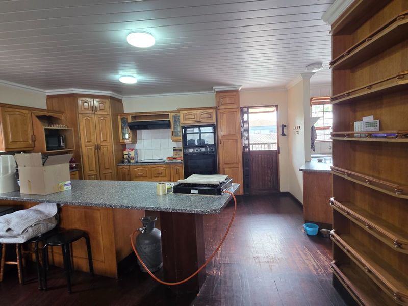 Spacious kitchen featuring extensive wooden cabinetry, built-in oven, extractor fan, and a central island with laminate countertops, finished with timber flooring and ceiling.