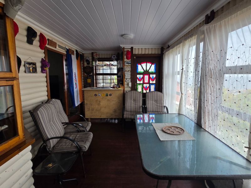 Enclosed patio area featuring timber wall cladding, a tongue and groove ceiling, and a decorative stained glass door with large windows.