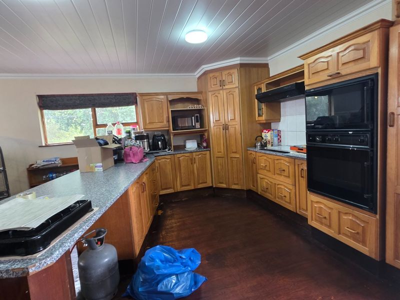 A dated kitchen featuring extensive wooden cabinetry, built-in double ovens, and a breakfast bar, offering significant potential for a modern renovation.