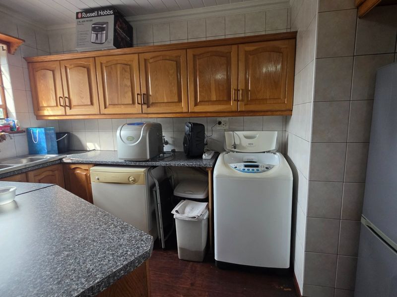 Functional laundry area featuring built-in wooden cabinetry, laminate countertops, and tiled splashbacks with dedicated plumbing connections for appliances.
