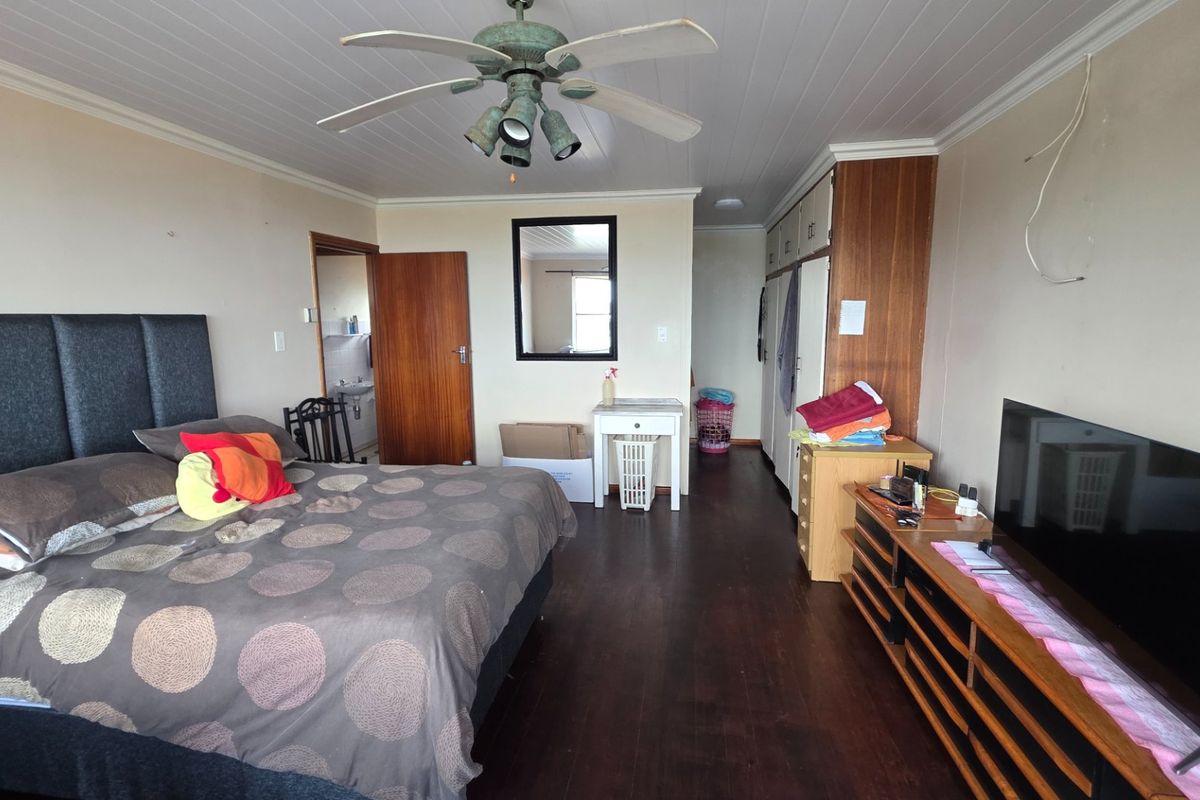 Spacious bedroom featuring timber flooring, built-in cupboards, a ceiling fan, and direct access to an en-suite bathroom.