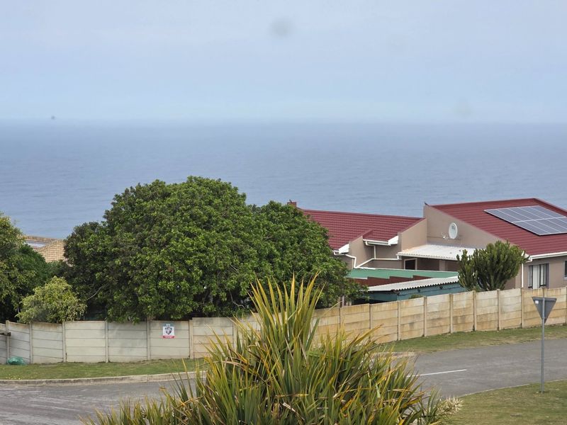 Elevated view overlooking the coastal landscape, featuring a residential property with solar panels and a secure boundary wall.