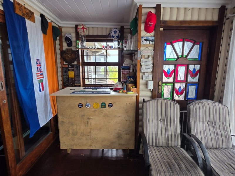A rustic bar area featuring timber wall paneling, a built-in bar counter, and a decorative stained glass entrance door.