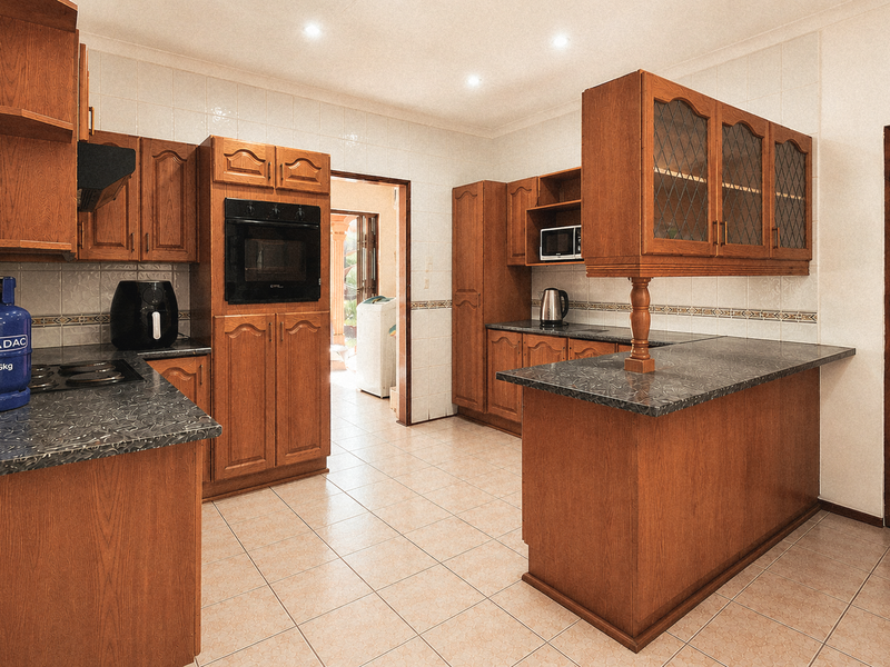 Traditional kitchen featuring extensive wooden cabinetry, laminate countertops, built-in oven, and tiled finishes, offering a functional layout with potential for modern updates.