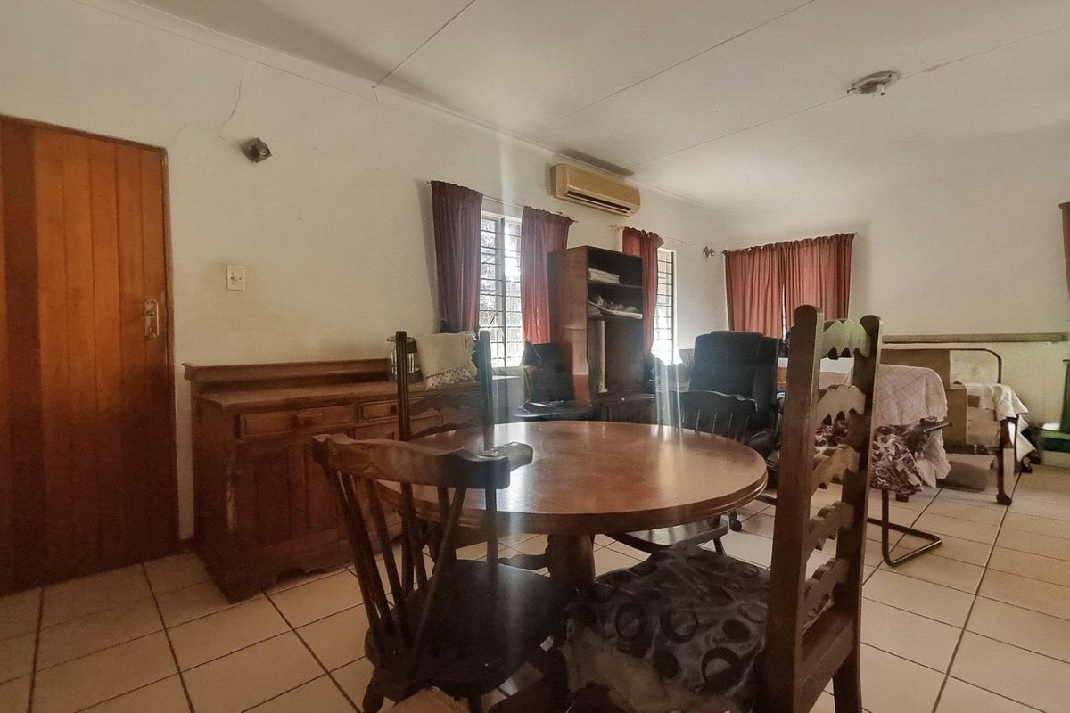 A living area featuring tiled flooring and a wall-mounted air conditioning unit, showing signs of wear including visible cracks on the wall.