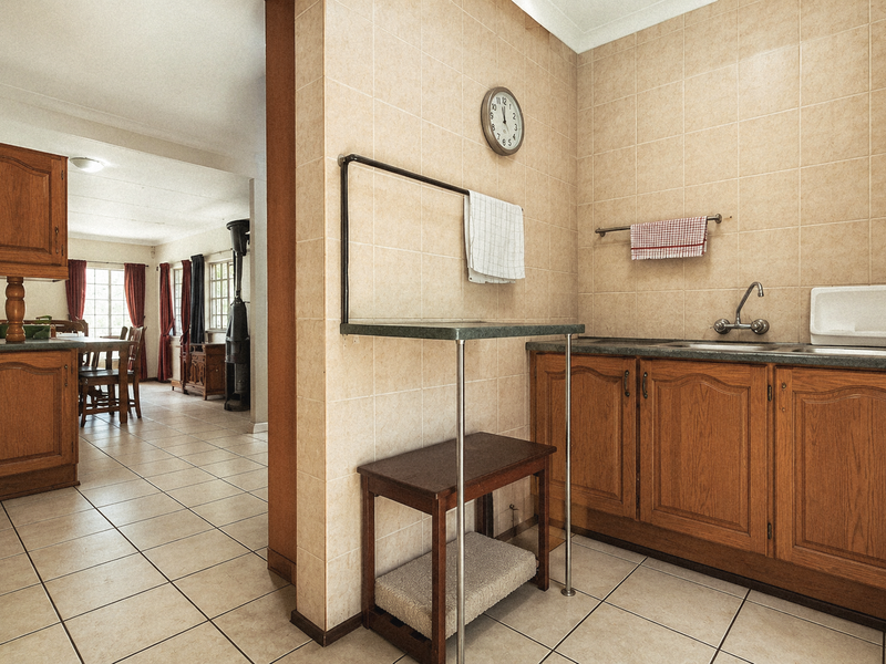 A functional scullery area featuring built-in wooden cabinetry, tiled walls, and a stainless steel sink, with an open transition to the adjacent kitchen space.