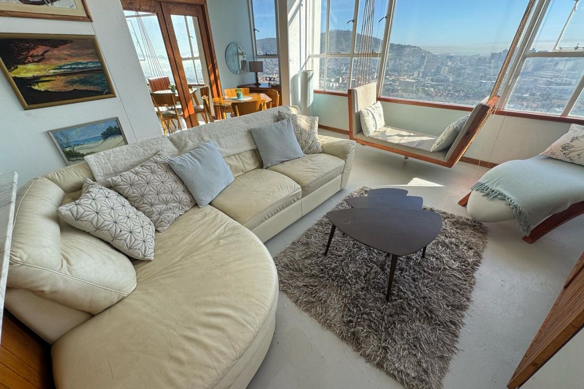 Bright living area featuring expansive floor-to-ceiling windows with panoramic city views and direct access to an adjacent dining space.