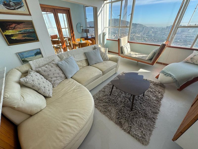 Bright living area featuring expansive floor-to-ceiling windows with panoramic city views and direct access to an adjacent dining space.