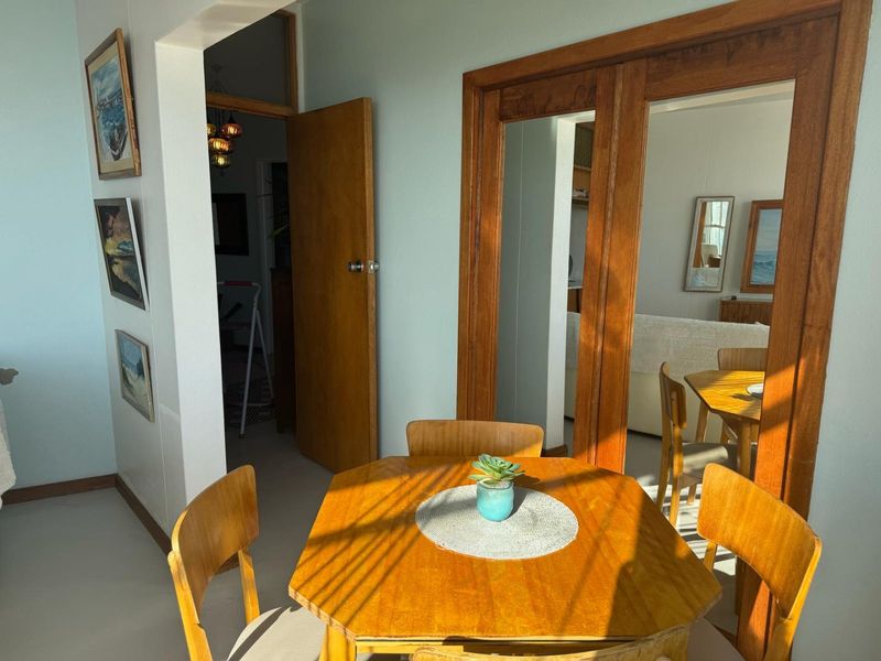 A dining area featuring a wooden door frame and an archway leading to an adjacent room, with natural light illuminating the space.