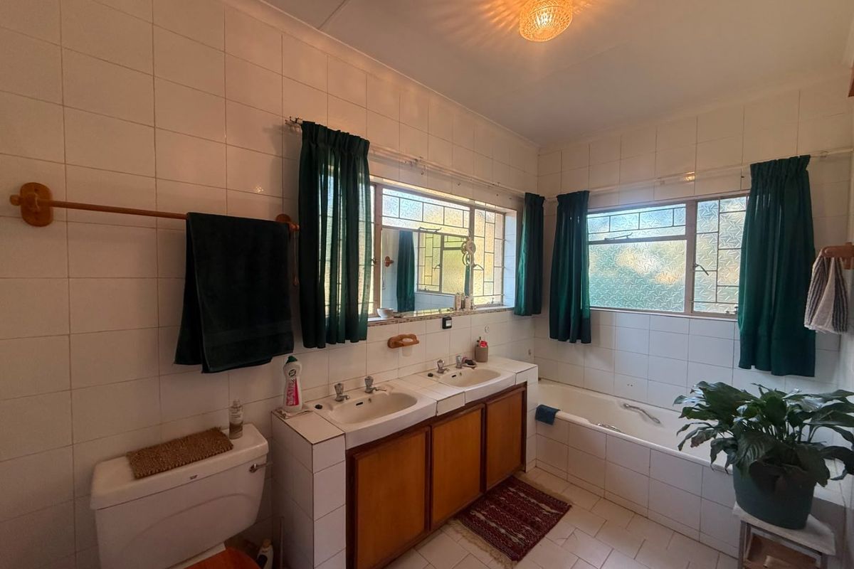 A functional bathroom featuring a double vanity with built-in cabinetry, a bathtub, and tiled finishes throughout.