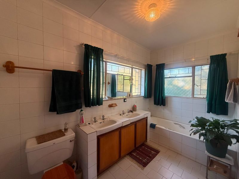 A functional bathroom featuring a double vanity with built-in cabinetry, a bathtub, and tiled finishes throughout.