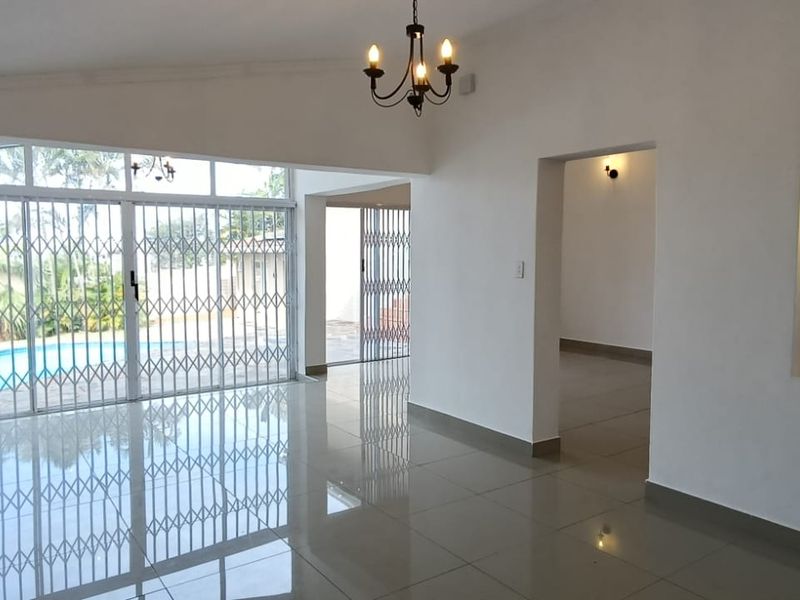 Spacious, light-filled living area featuring polished tile floors, decorative wall niches, and large sliding doors providing direct access to the pool area.
