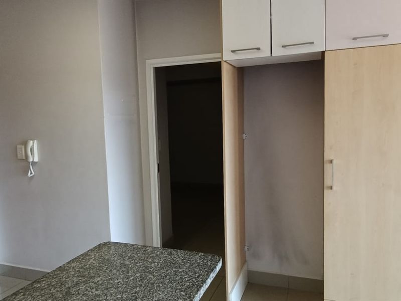 A functional kitchen area featuring built-in cabinetry, a granite countertop, and tiled flooring, providing a clean and practical space for culinary activities.