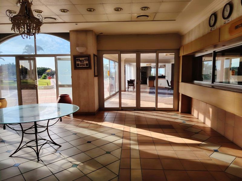 Spacious building entrance featuring tiled flooring, a reception counter, and large glass sliding doors providing access to the outdoor area.