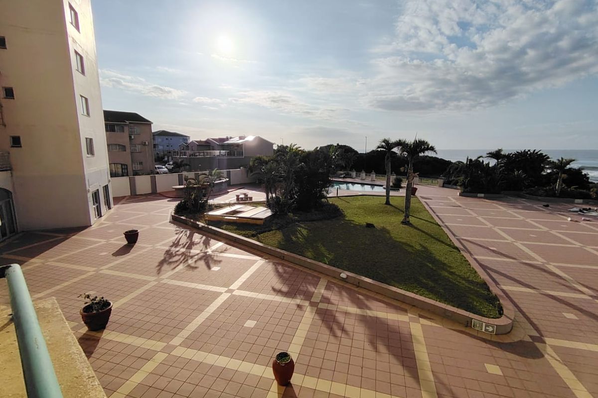 A spacious communal courtyard area featuring a swimming pool, landscaped garden, and paved walkways, offering a pleasant outdoor space for residents.