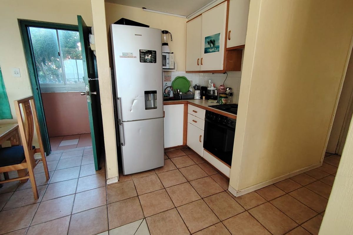 Compact kitchen featuring built-in cabinetry, oven, and hob, with direct access to an adjacent balcony area.