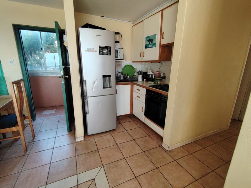 Compact kitchen featuring built-in cabinetry, oven, and hob, with direct access to an adjacent balcony area.