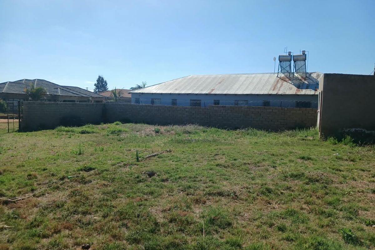 A view of the rear yard featuring a perimeter wall, corrugated metal roofing, and a solar water heating system.