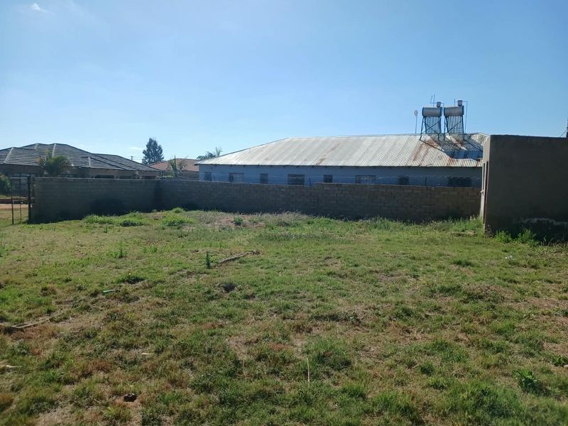 A view of the rear yard featuring a perimeter wall, corrugated metal roofing, and a solar water heating system.