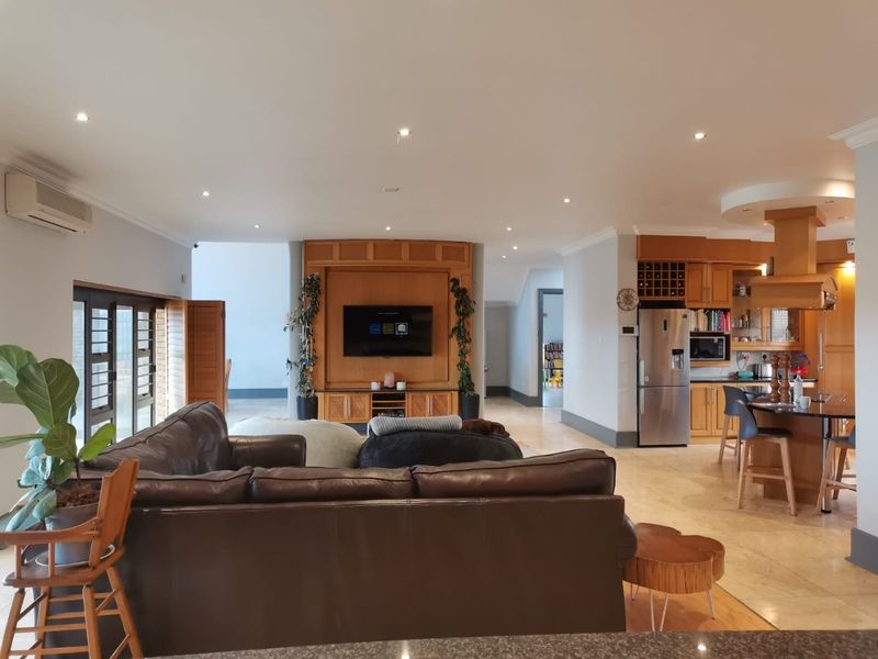 Spacious open-plan living area featuring a modern kitchen with island, built-in cabinetry, and tiled flooring, seamlessly flowing into the lounge space.