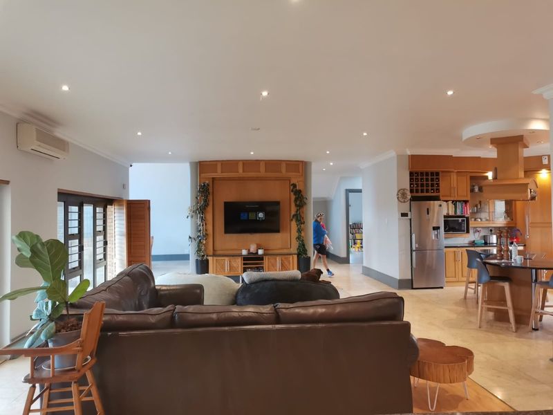 Spacious open-plan living area featuring a modern kitchen with island, built-in cabinetry, and integrated appliances, seamlessly flowing into the lounge space.
