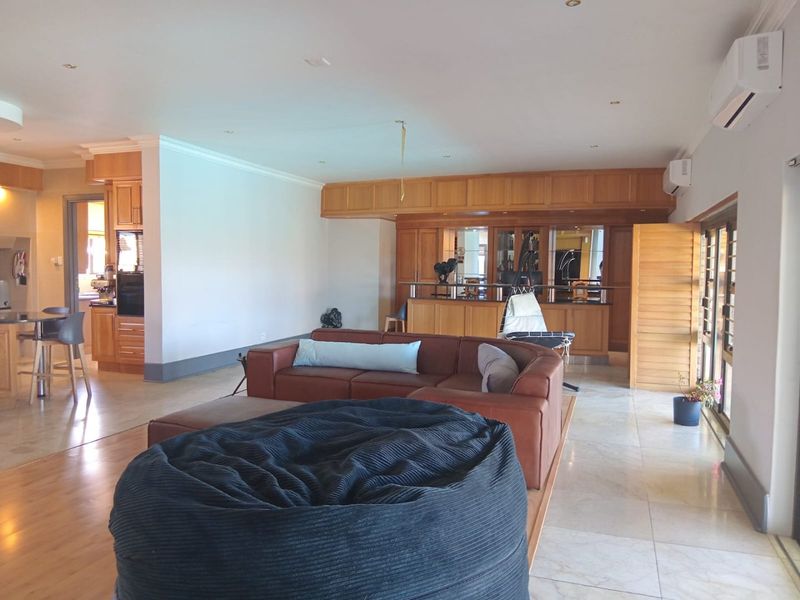 Spacious open-plan living area featuring a built-in wooden bar, tiled flooring, recessed lighting, and split-system air conditioning units.