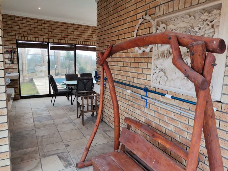 A covered outdoor patio area featuring exposed brick walls, tiled flooring, and sliding glass doors that provide access to the pool area.