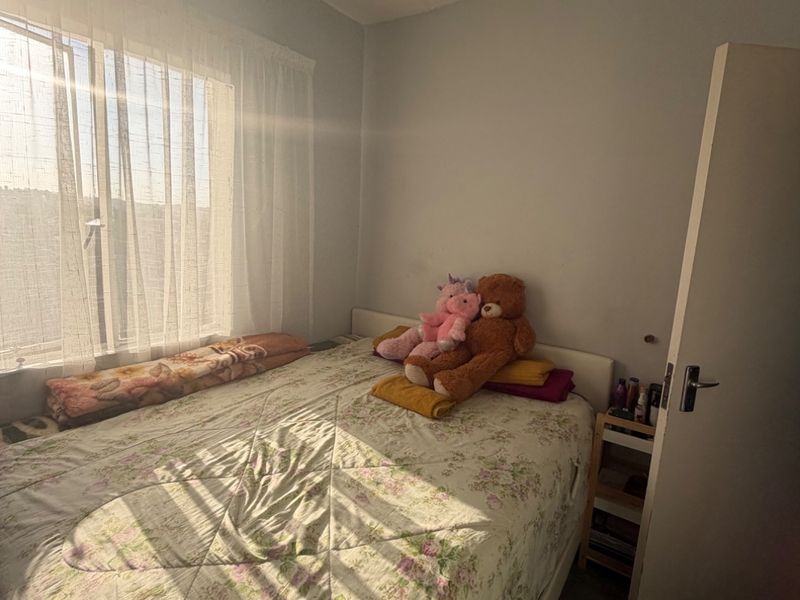 A standard bedroom featuring a window with natural light, a ventilation grille, and a door, providing a functional living space.