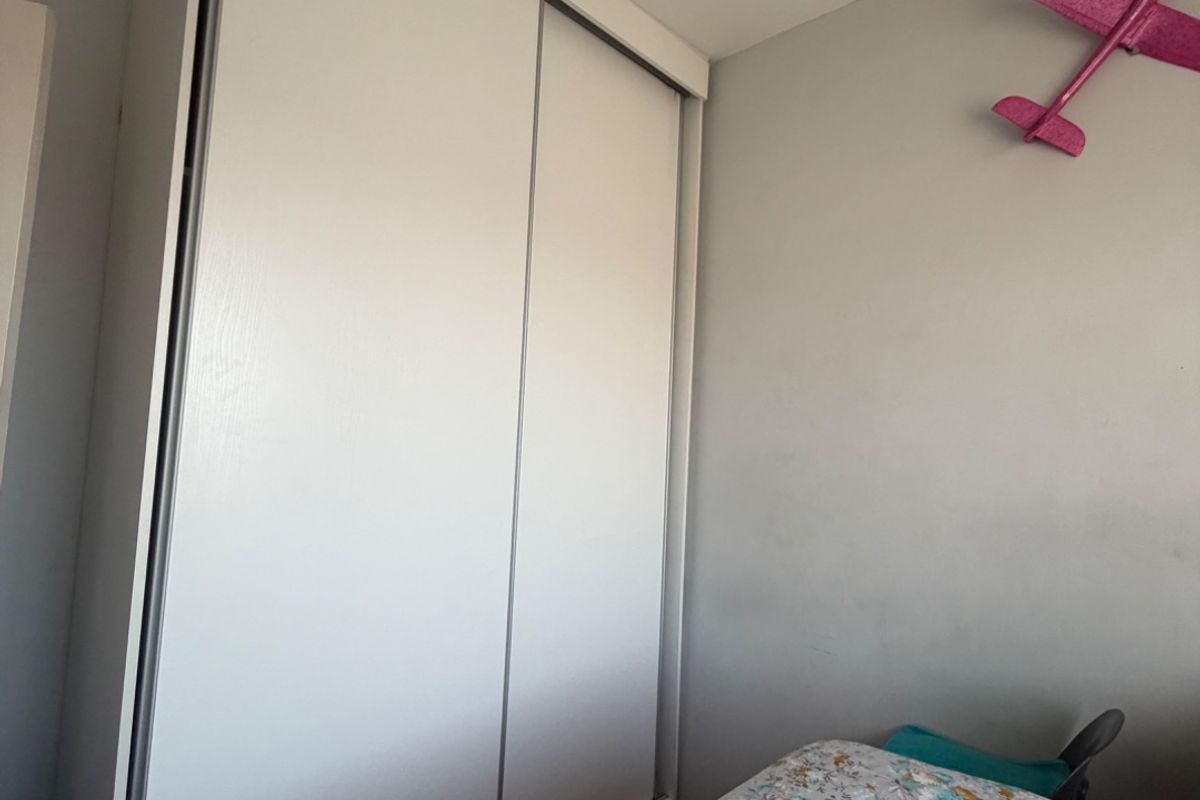 A bedroom featuring a white built-in sliding door wardrobe providing ample storage space.
