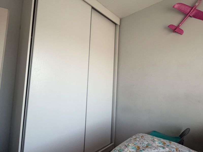 A bedroom featuring a white built-in sliding door wardrobe providing ample storage space.