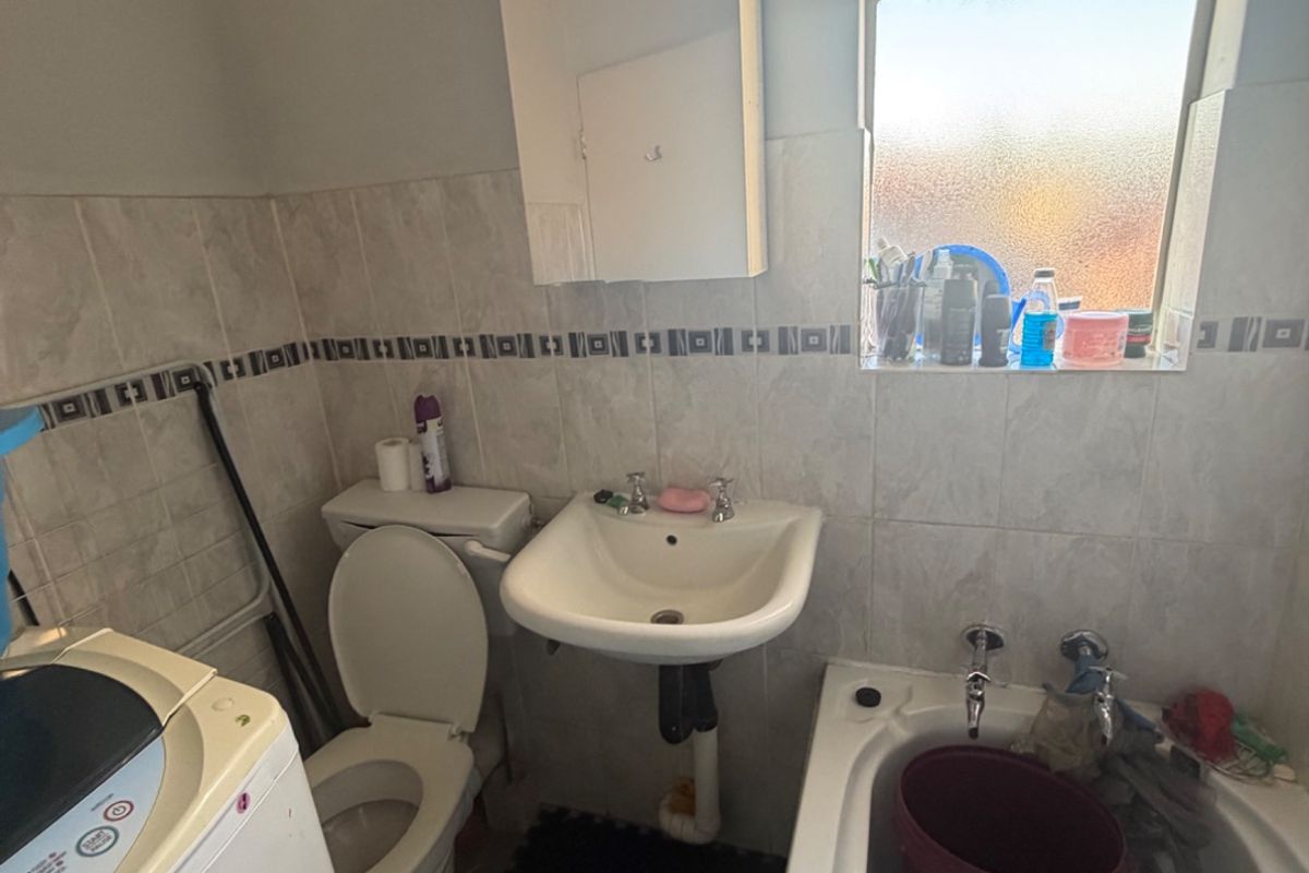 Compact bathroom featuring a bathtub, pedestal basin, and toilet with tiled splashbacks and a functional medicine cabinet.