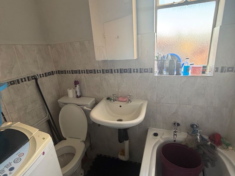 Compact bathroom featuring a bathtub, pedestal basin, and toilet with tiled splashbacks and a functional medicine cabinet.